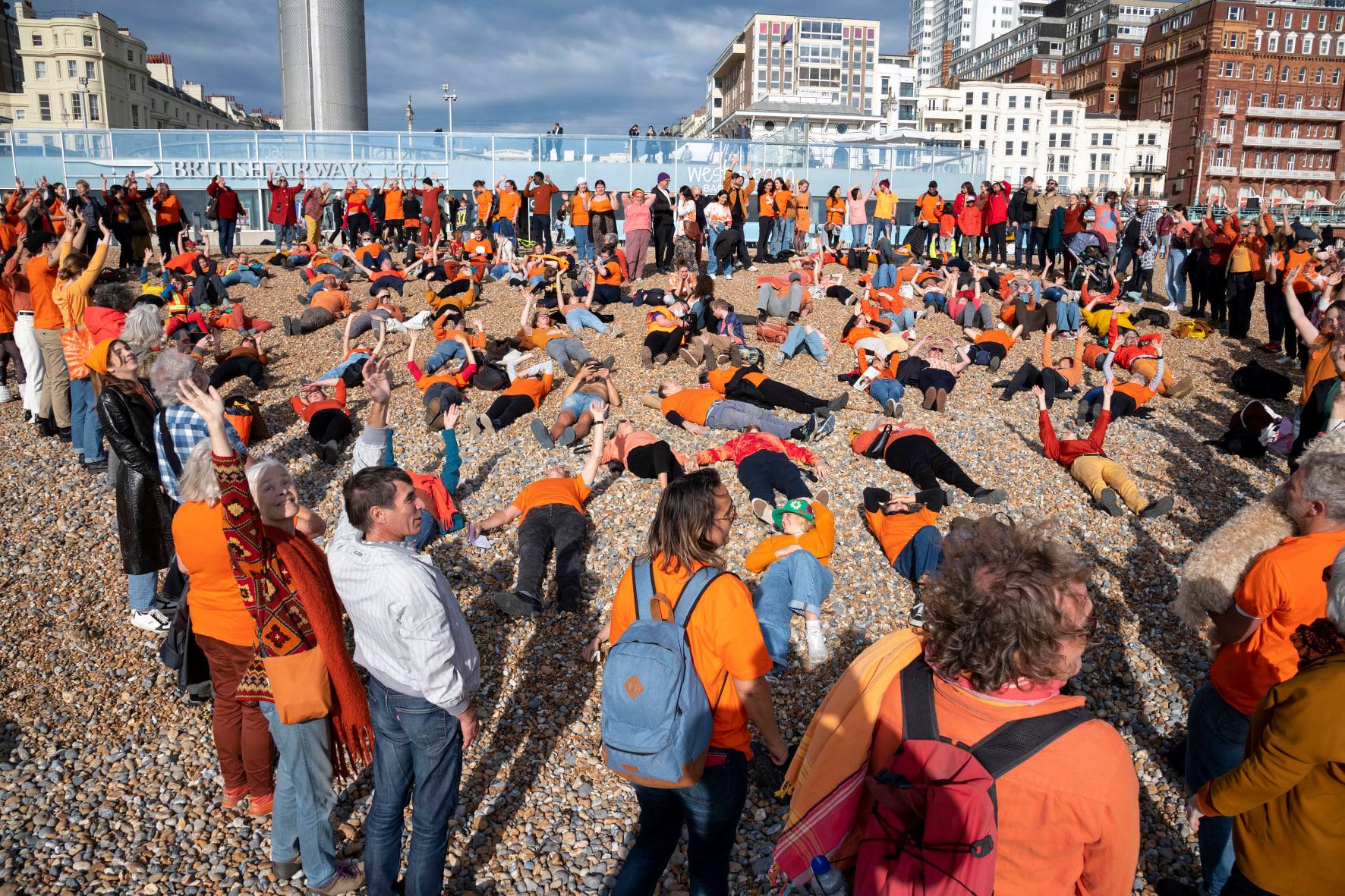 People laying down on the sand, wearing orange